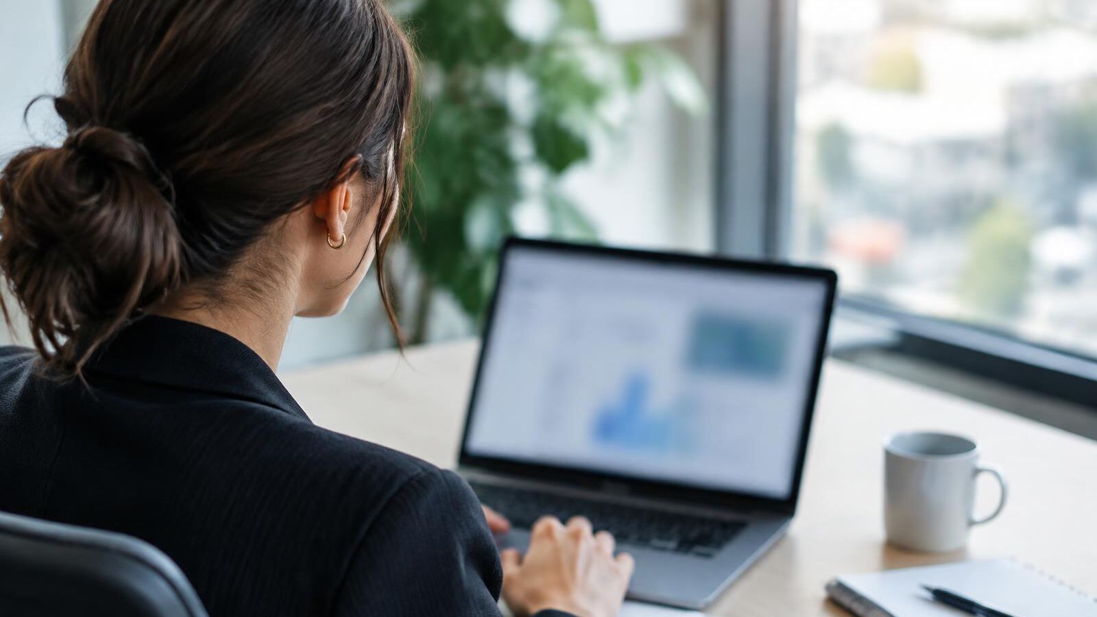 An analyst works with AI tools on a laptop in a quiet modern office, the screen softly blurred
